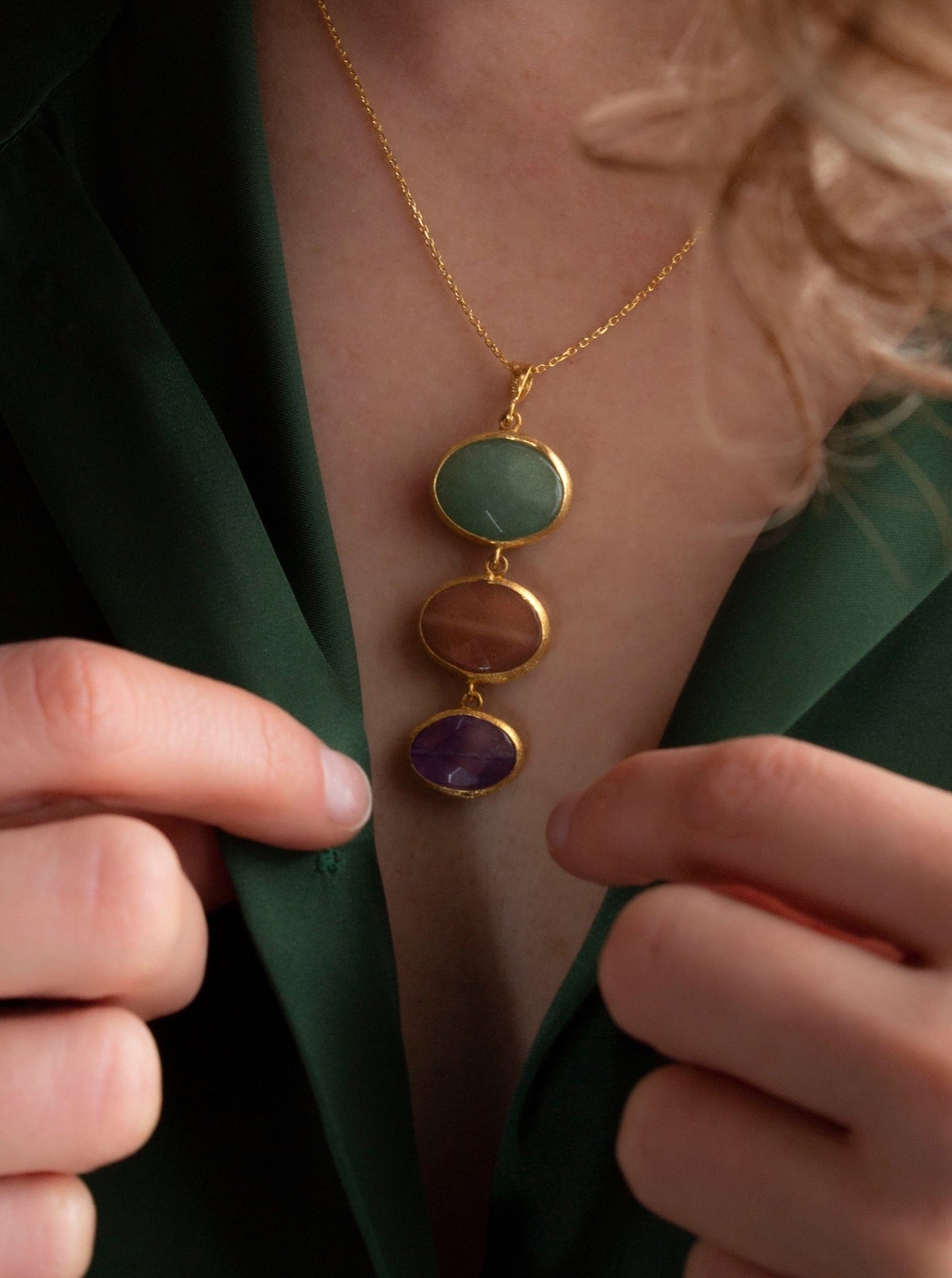 Close up of a woman with a green shirt wearing Charites necklace, green aventurine, pink moonstone, amethyst pendant.