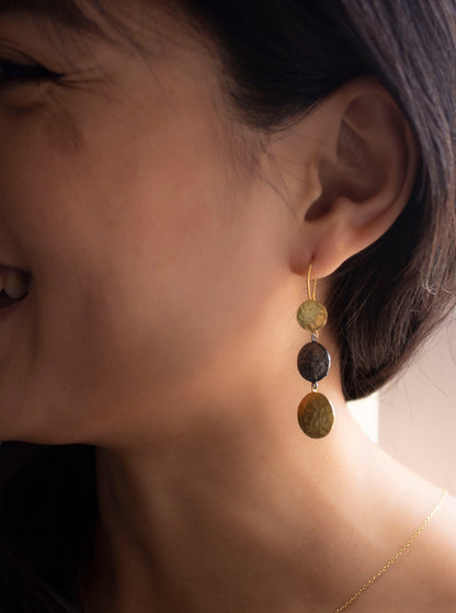 Happy girl wearing minimal pendant earrings with gold and silver oxidised connected circles