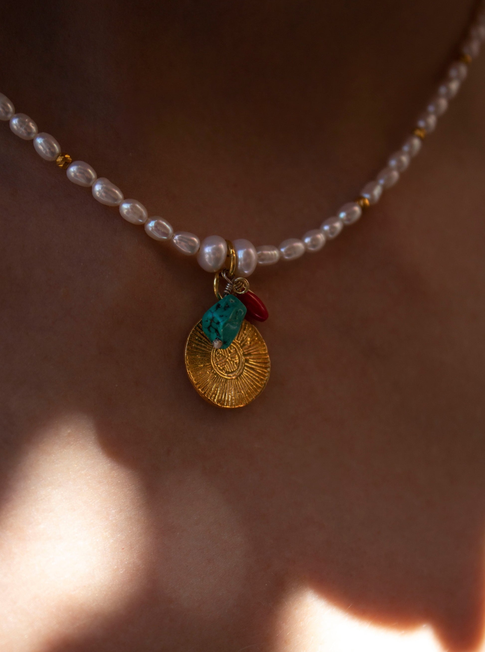 Detail of the Cybele necklace, showing the symbol of sun, the turquoise and coral