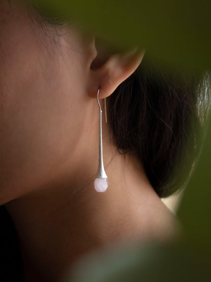 Sabiria's long silver earrings with briolette cut light pink quartz gemstone seen through plants